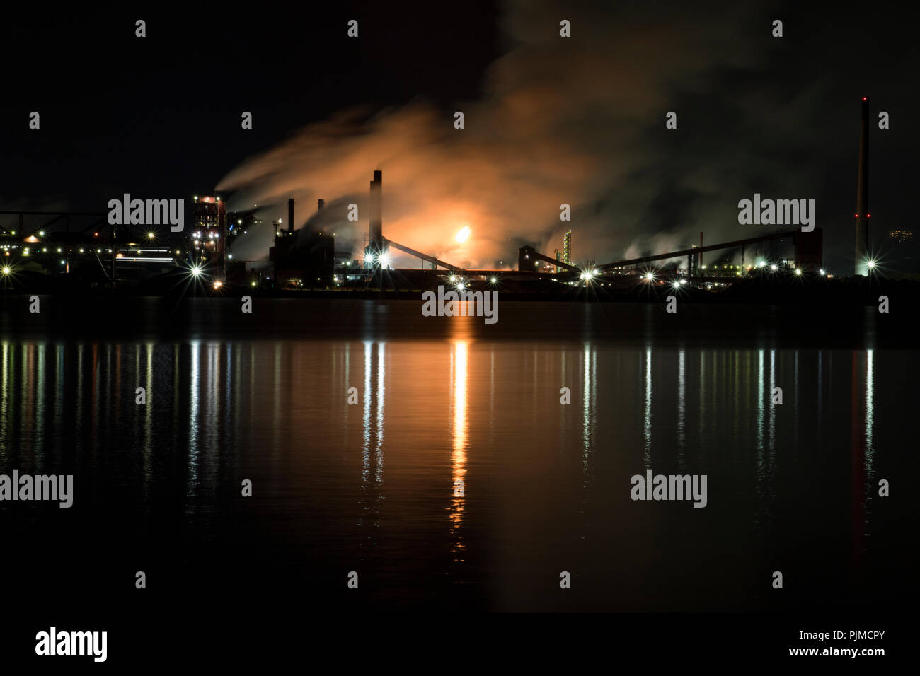 Las fábricas contaminantes y aumentar el calentamiento global. Ocupado en la acería industrial bombeo nocturno de humo en el medio ambiente. Foto de stock