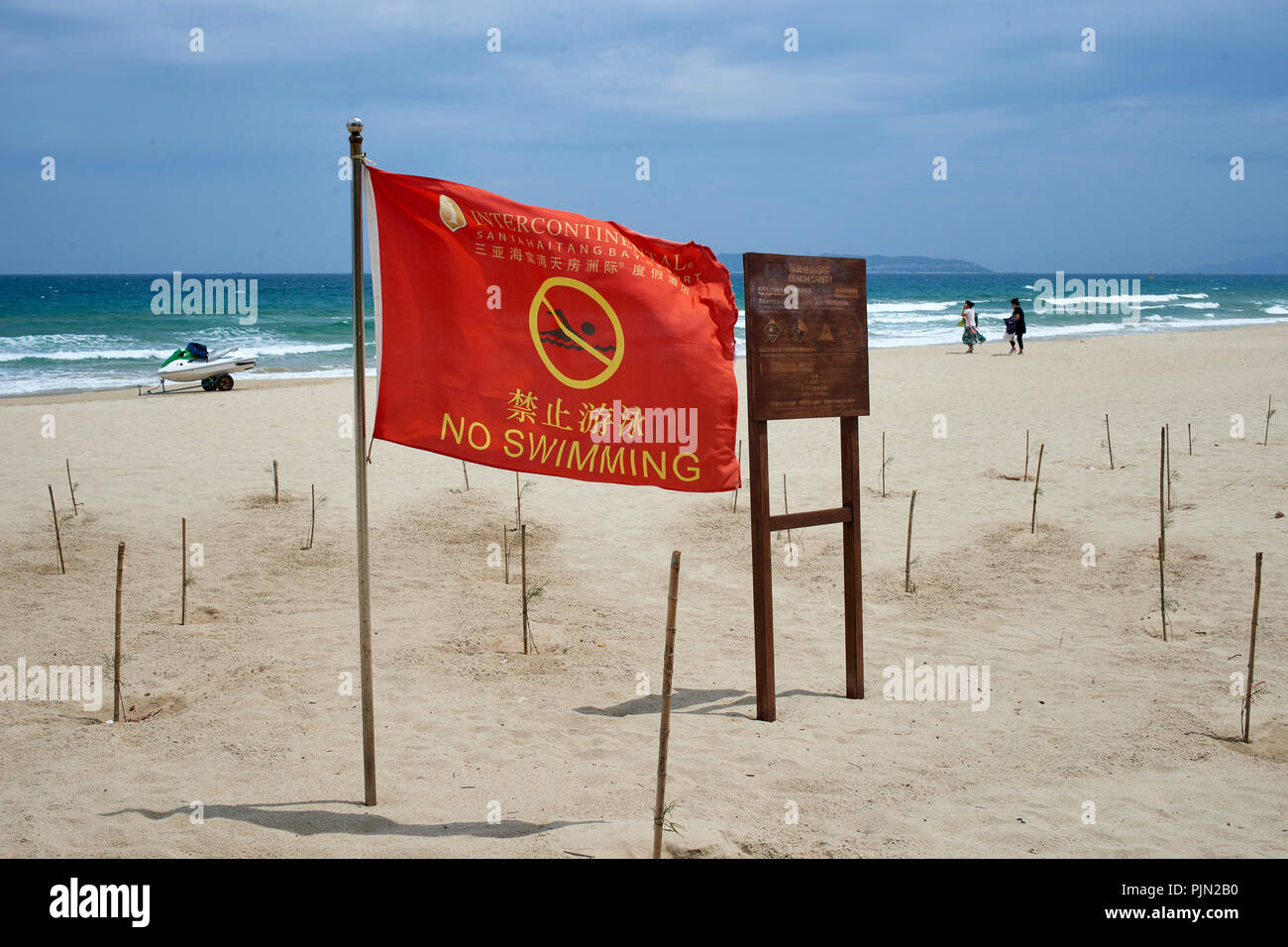 Playa de arena en la playa, Sanya, en un ventoso día de verano. "No nadar' banderas visibles Foto de stock