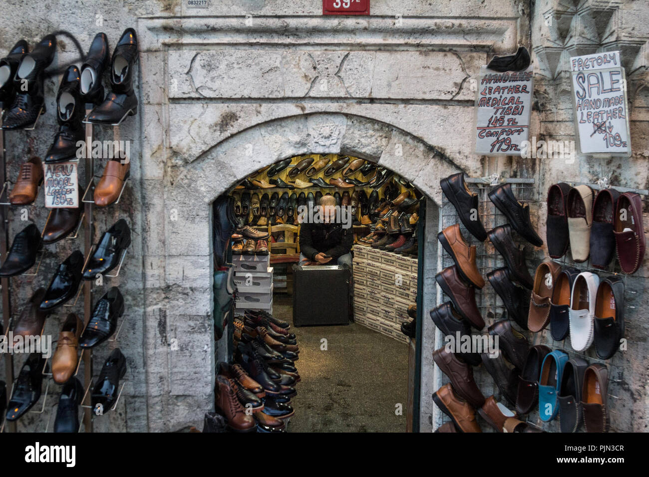 Estambul, Turquía - Diciembre 28, 2015: el vendedor turco descansando y comprobando su smartphone en su tienda, venta de zapatos y botas, en la distribución de Beyazit Foto de stock