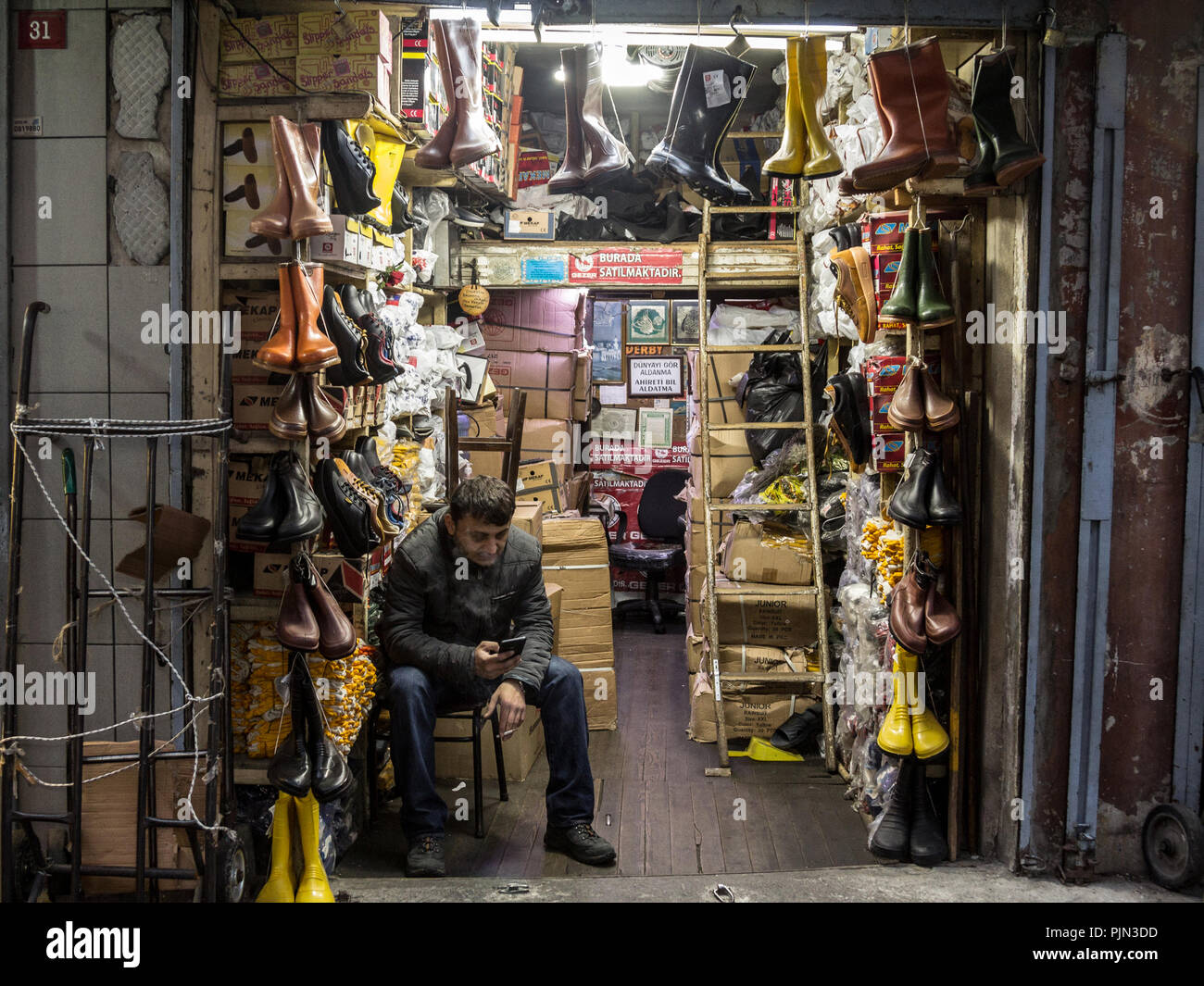Estambul, Turquía - Diciembre 29, 2015: el vendedor turco fumar cigarrillos delante de su tienda, venta de zapatos y botas, cerca del Bazar de las especias, en la Foto de stock