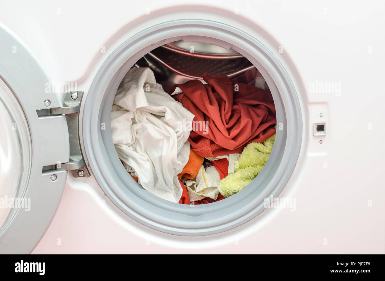 Cerca de una lavadora cargada con ropa de color rojo y blanco, colores que  no deberían mezclarse Fotografía de stock - Alamy