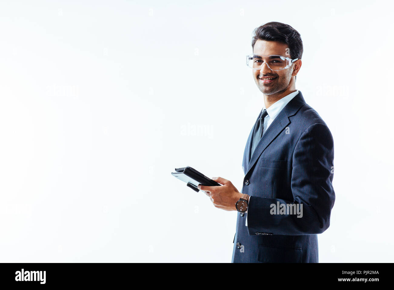 Retrato del hombre en traje de negocios la celebración de tableta electrónica pad y gafas protectoras mirando a la cámara, aislado sobre fondo blanco studio Foto de stock
