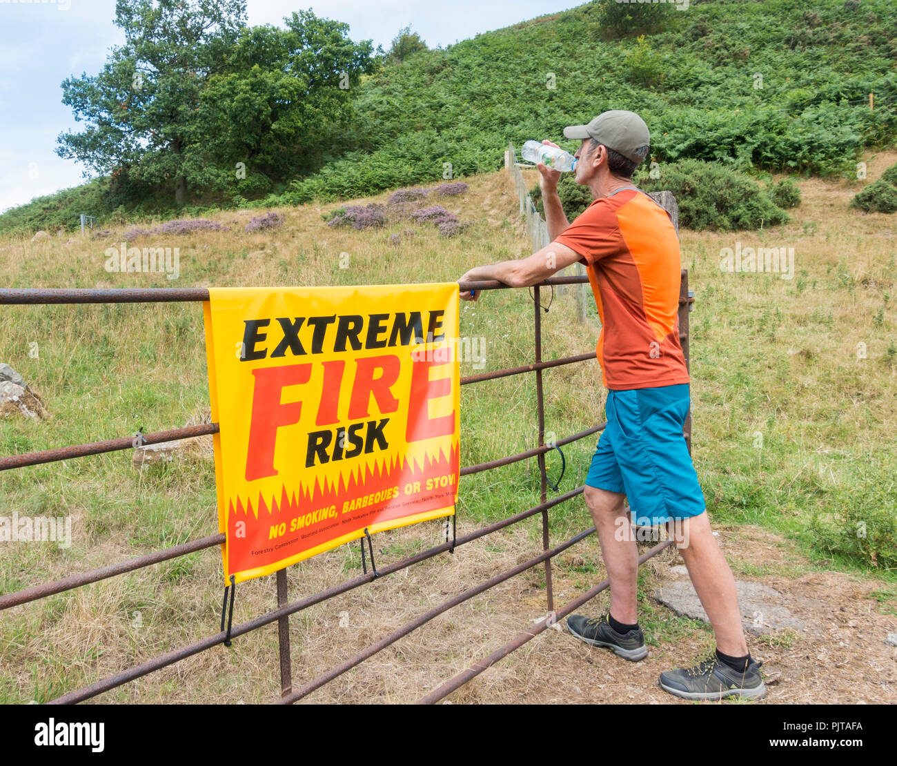 Ola de calor en el REINO UNIDO: Trail Runner junto al signo de riesgo de incendios extremos en el parque nacional North York Moros. Verano 2018 Foto de stock