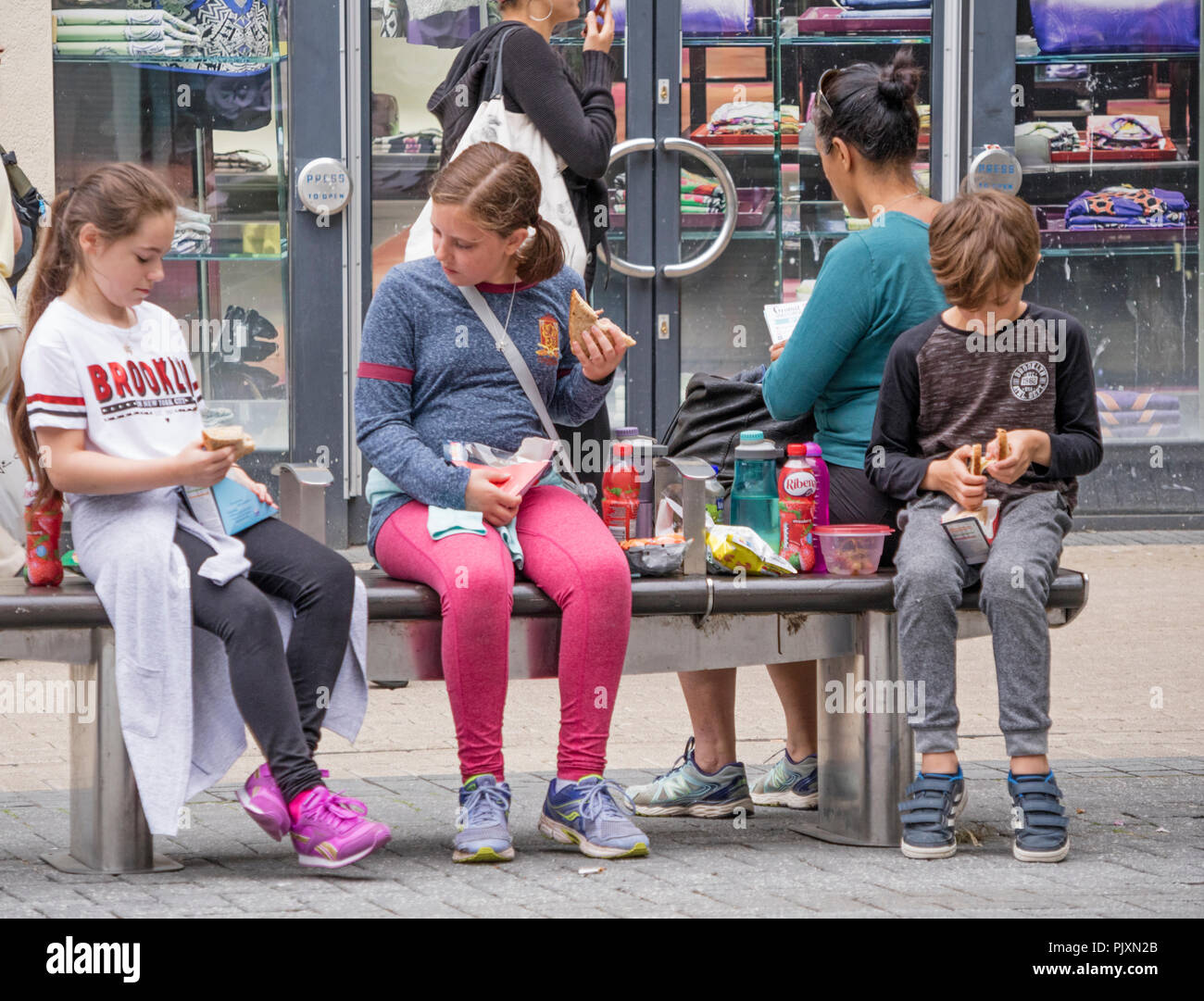 Los niños que comen tienda compraron comida rápida, mientras que las compras en Bristol, Inglaterra, Reino Unido. Foto de stock