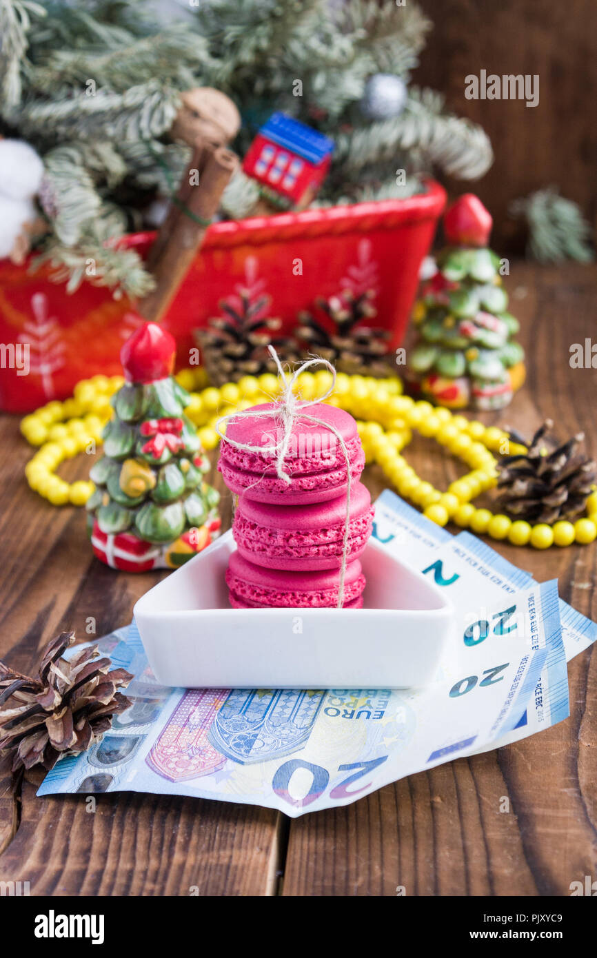 Pink macarons y veinte euros con decoraciones de Navidad sobre fondo woooden Foto de stock