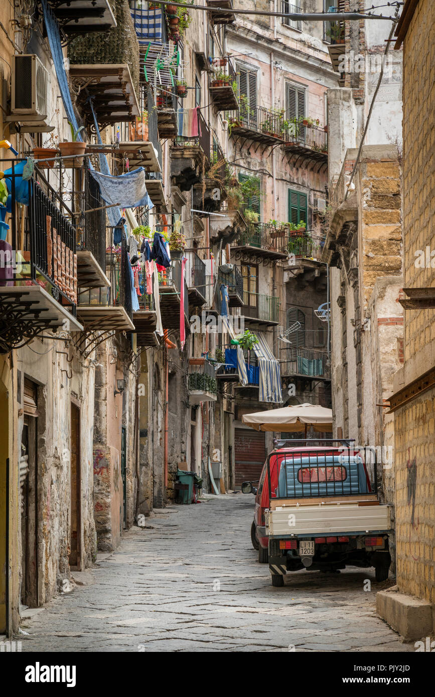 Una escena en la calle Palermo con lavado colgando de los balcones de los apartamentos residenciales y un tradicional de tres ruedas Piaggio Ape la camioneta estacionada outsid Foto de stock