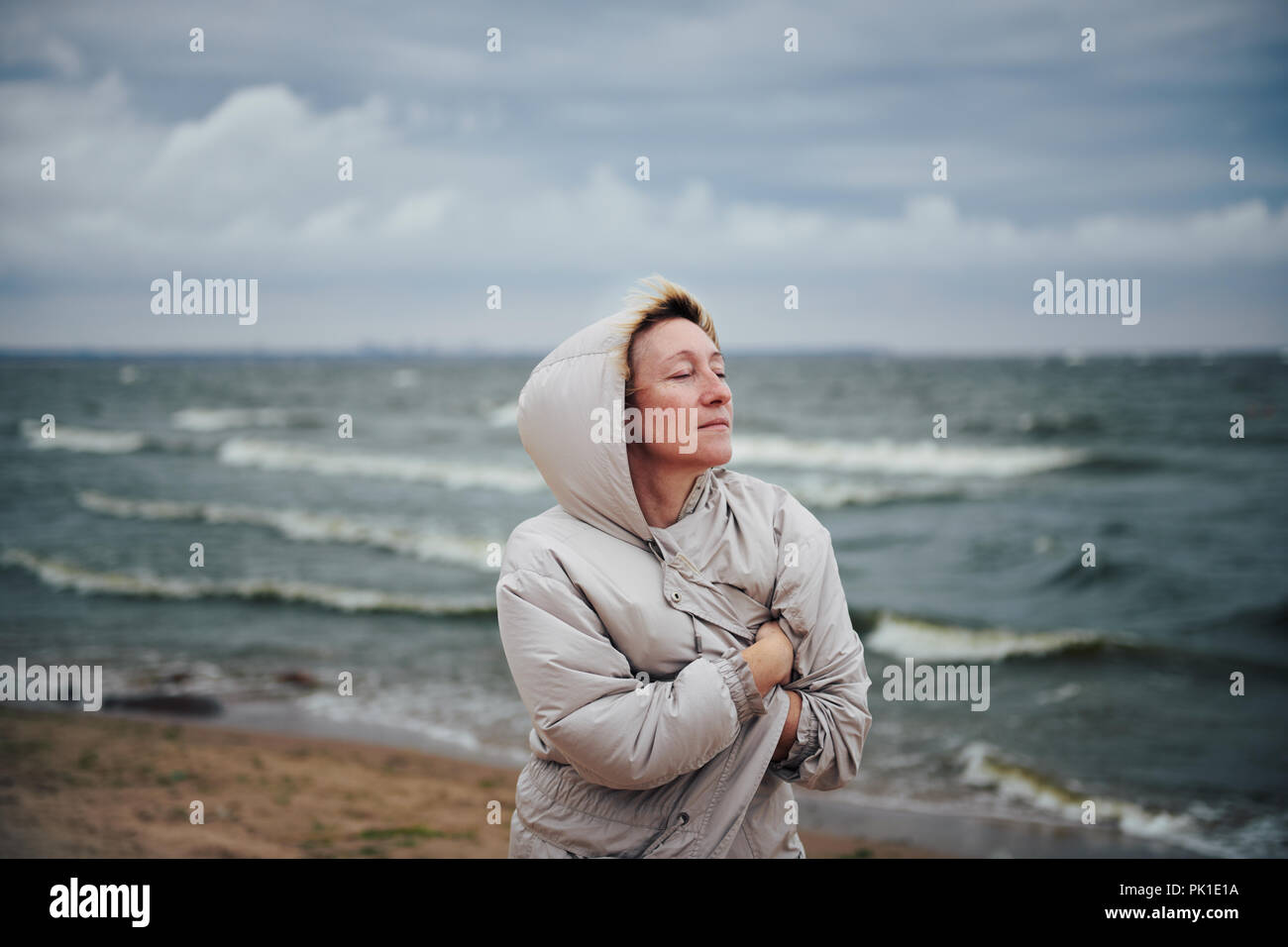 Chaqueta de Mujer adulta en pie cerca del mar Foto de stock