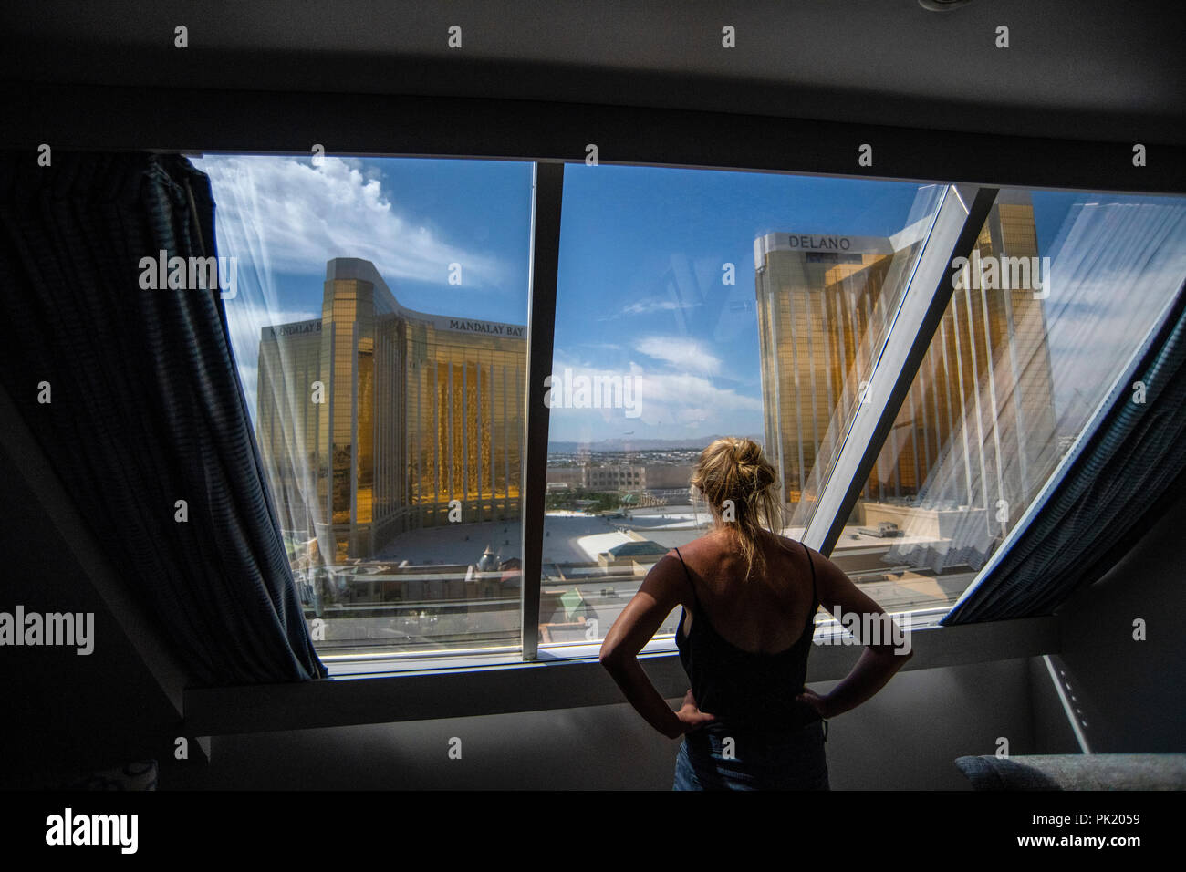 Una mujer mira fuera de una habitación de hotel en el Luxor Hotel and Casino hacia el Mandalay Bay y Delano resorts en Las Vegas, Nevada, EE.UU. Foto de stock