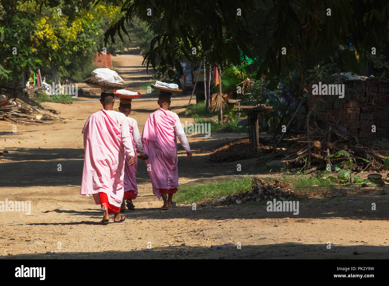 Tres monja budista birmano camina en una carretera de Nyaung U, Bagan, Myanmar (Birmania). Foto de stock