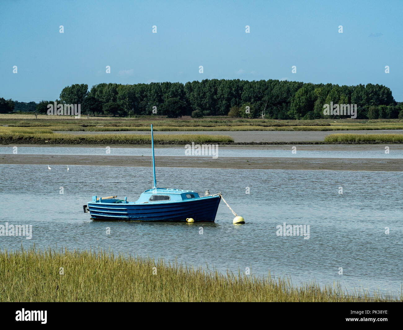 Un tranquilo día en el río Alde en Iken incluyendo un barco anclado azul en primer plano Foto de stock