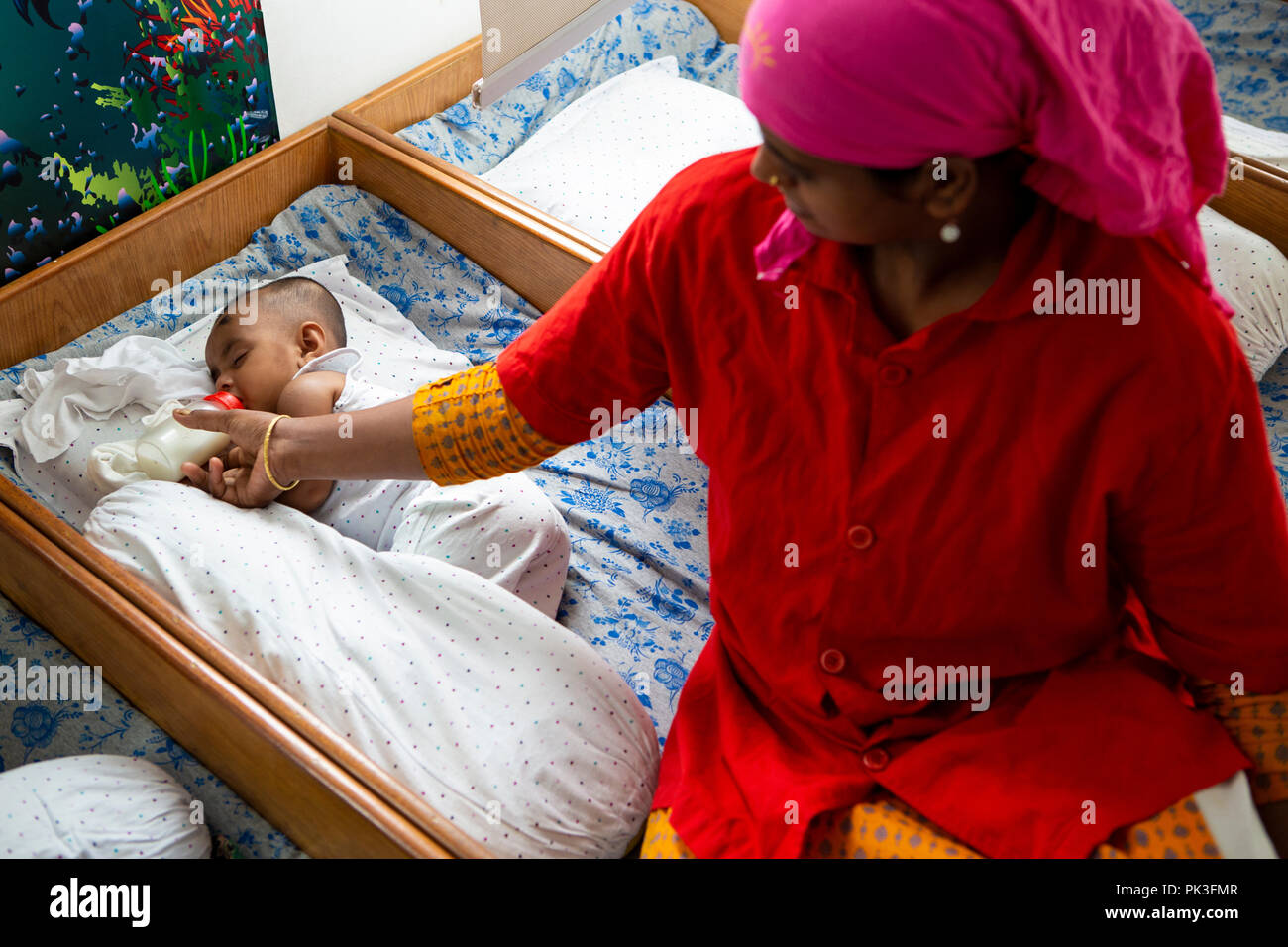 Un bebé alimentado mientras duermen en el centro de atención infantil en una fábrica de ropa en Dhaka, Bangladesh Fotografía de stock - Alamy