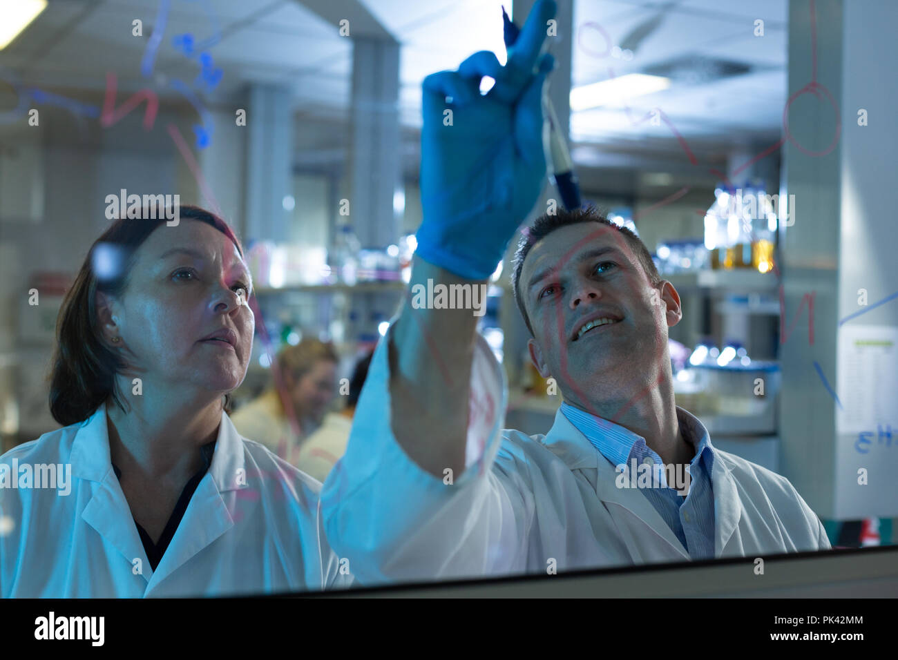 Equipo de científicos discutiendo sobre la placa de vidrio Foto de stock