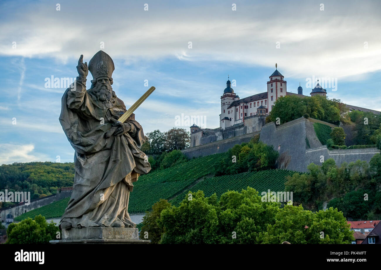 San Kilian estatua en la Alte Mainbrücke, Würzburg con Marienberg Fortress en segundo plano. Foto de stock