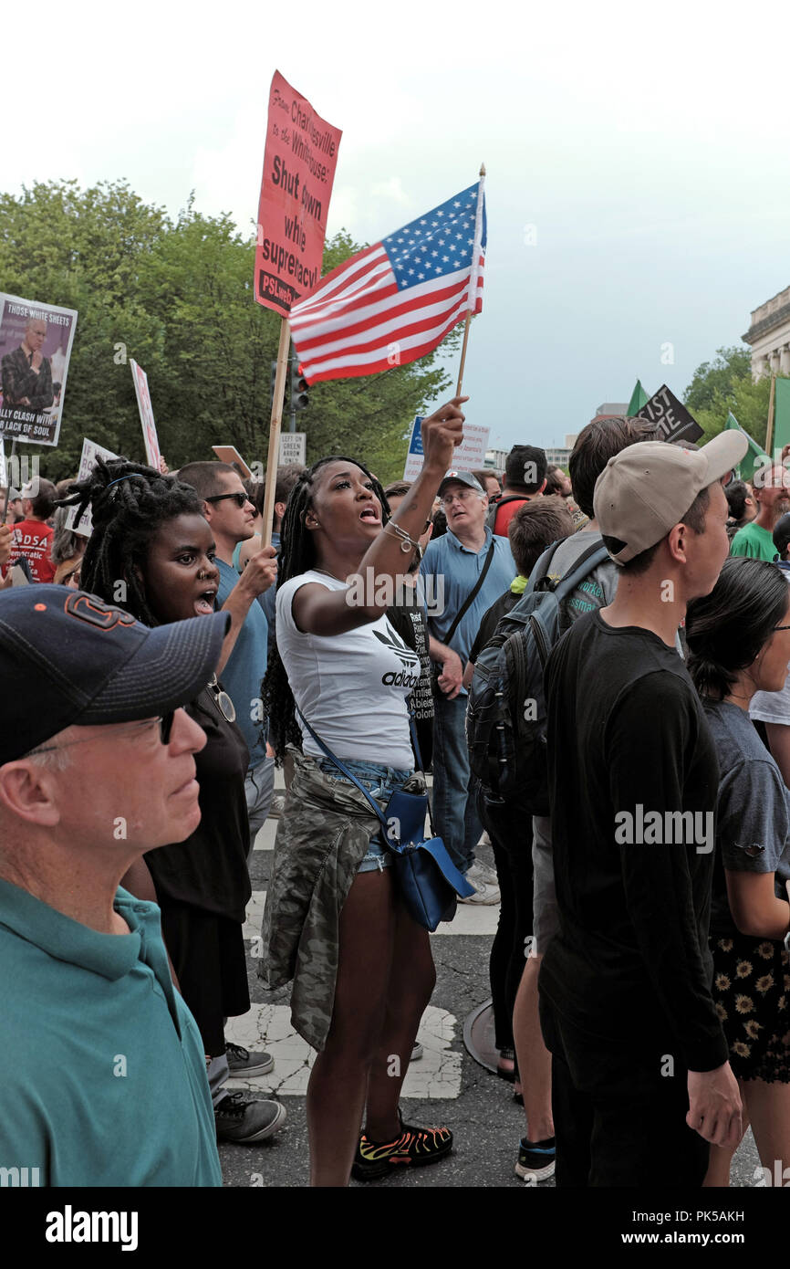 Mujer Negra sostiene una bandera americana como ella marchas en protesta por la denuncia del racismo y el odio celebrada el 12 de agosto de 2018, en Washington DC. Foto de stock