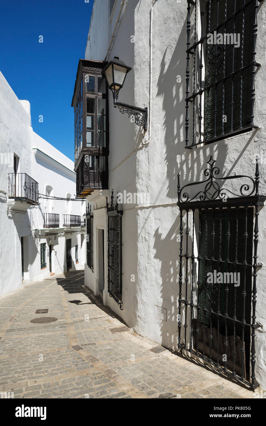 Callejón y brillantemente encalada fachada parrilla, casas en la cima de la ciudad de Vejer de la Frontera, Cádiz Foto de stock