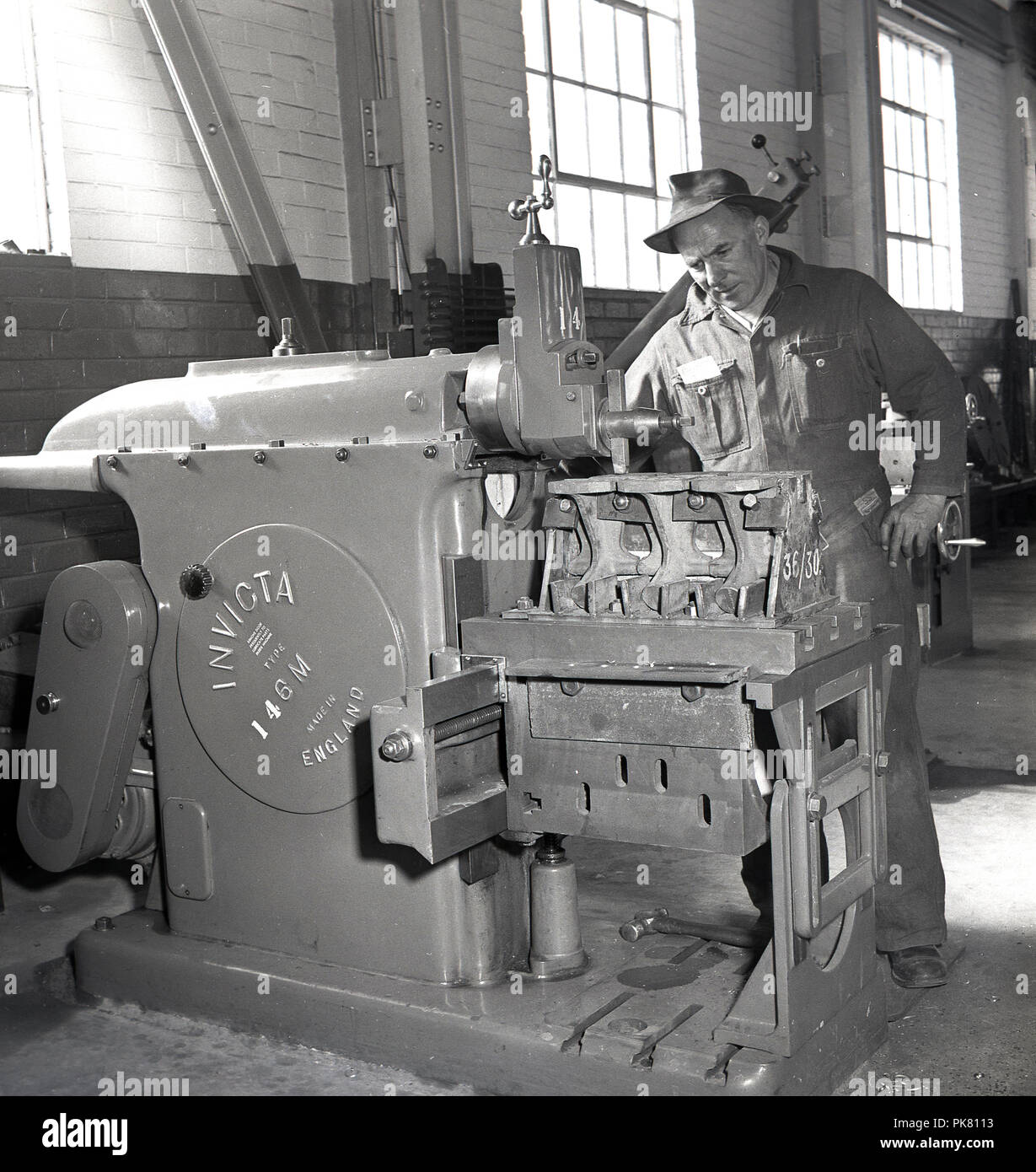1950s, históricos, un trabajador con una de hierro fundido de 'made in  England', una máquina, un tipo Invicta 146M torno, maquinaria utilizada en  el corte y procesamiento de las materias metales Fotografía