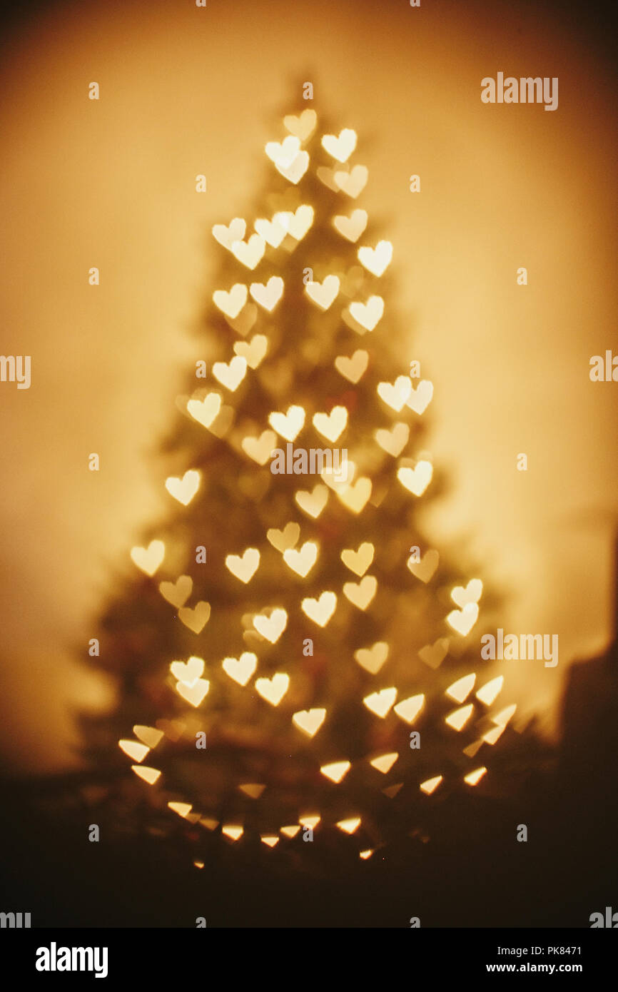 Hermoso árbol de navidad luces doradas corazones en sala festiva. Navidad  resumen antecedentes, desenfoque desenfoque bokeh de color amarillo  brillante corazones en christm Fotografía de stock - Alamy