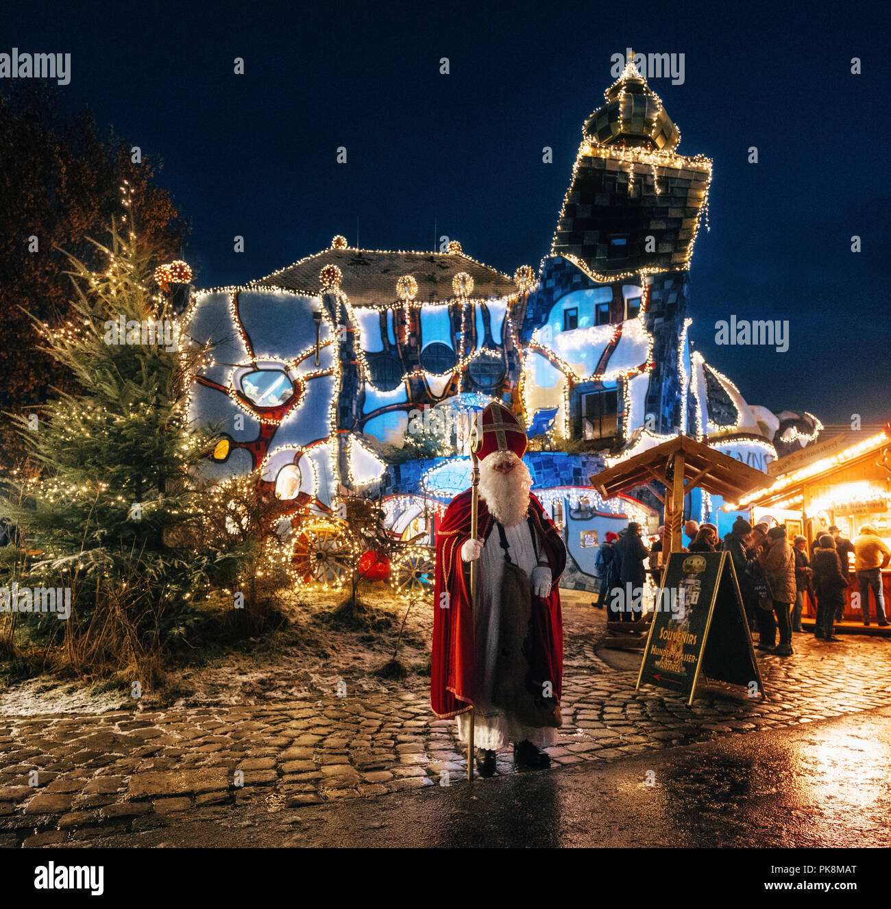 Abensberg, Alemania - 8 de diciembre de 2017: Saint Nicholaus está delante de Hundertwasser, el Museo de Arte Kunsthaus con iluminaciones de Navidad y cargas de Foto de stock
