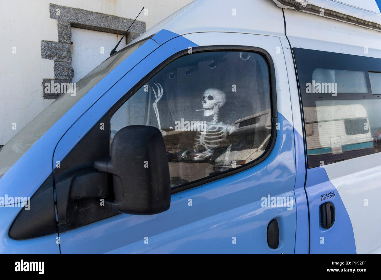 Un esqueleto sentado en el asiento del pasajero de una furgoneta camión. Foto de stock