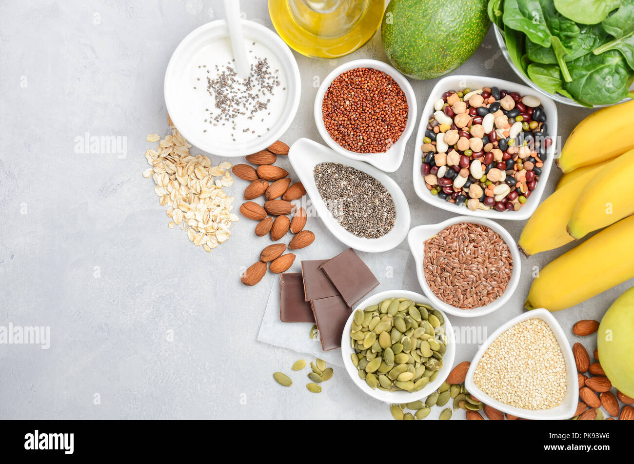 Comida sana nutrición dietética concepto. Plátano, chocolate, espinacas, aguacate, manzana, quinoa, chia, semillas de lino, yogur, almendras, frijoles, avena, semillas de calabaza. Foto de stock