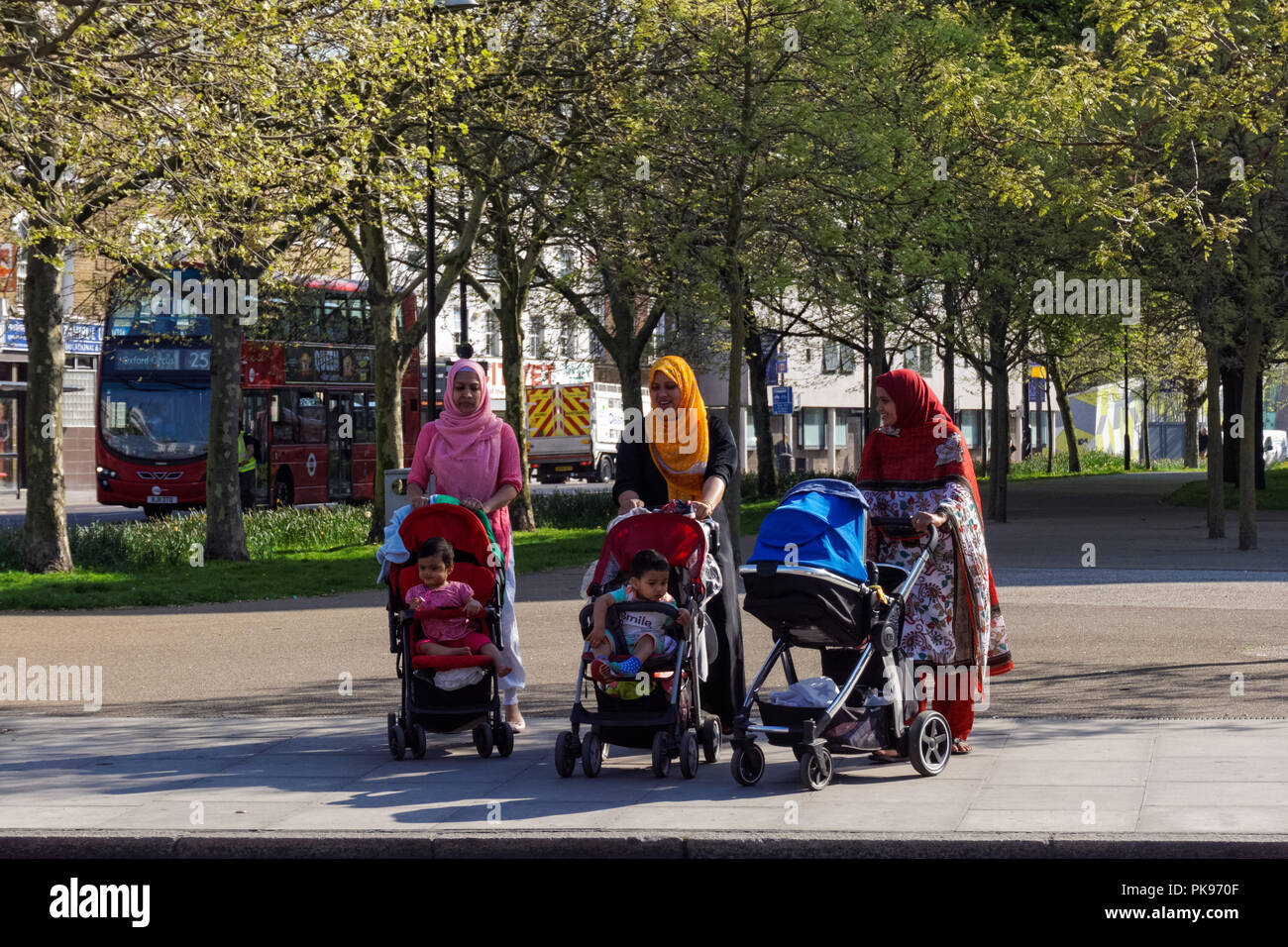 Las mujeres de minorías étnicas con los niños caminando en Stepney Green, Londres England Reino Unido Foto de stock