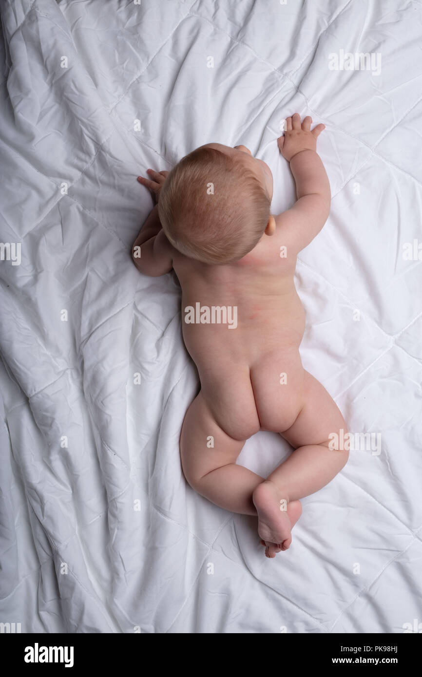 Pequeño bebé recién nacido intentar en la de cama blanca visto desde arriba mostrando su little Fotografía de stock - Alamy