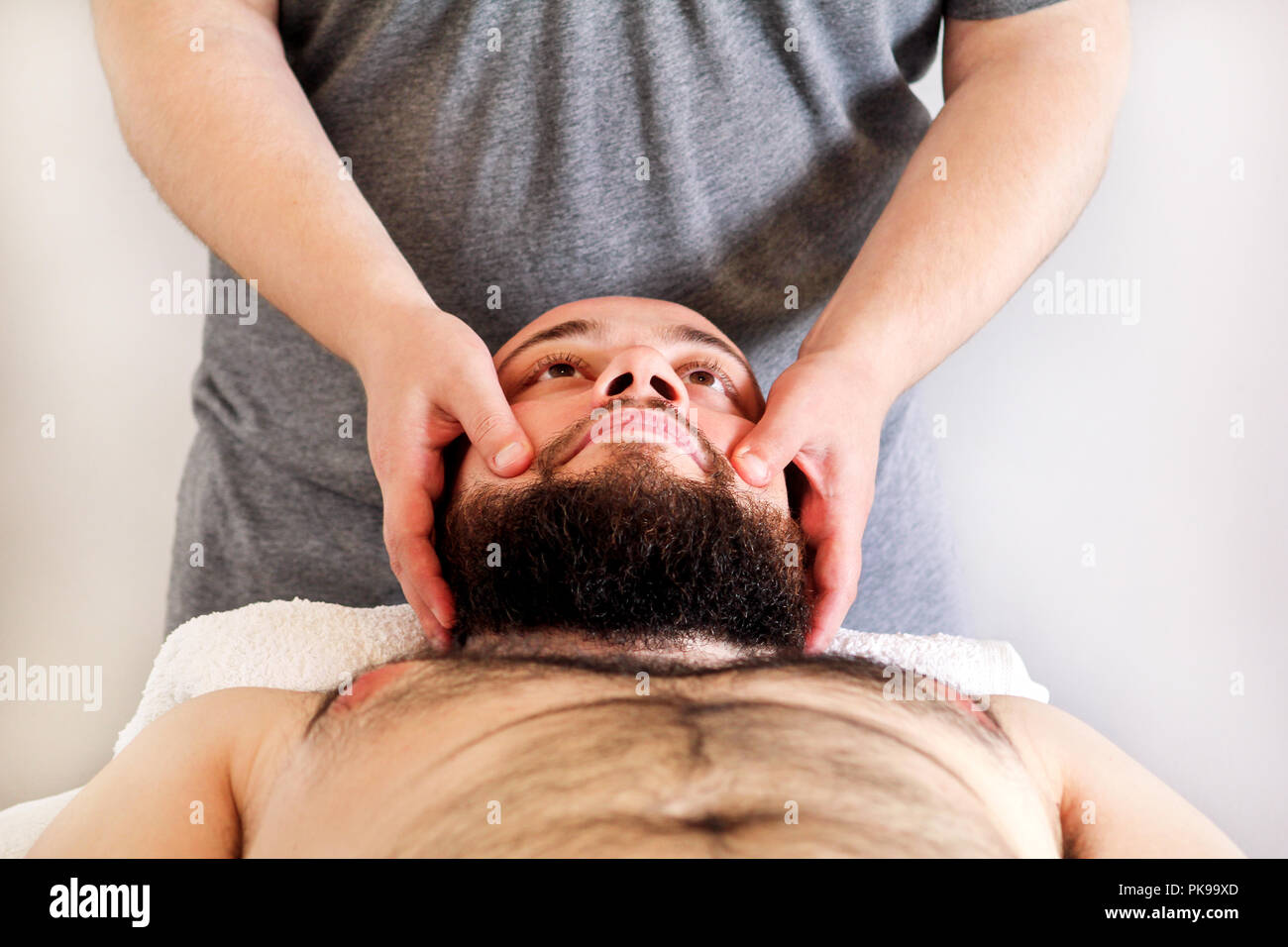 Estudio de masajes. Los hombres manos masajista para masajes de la cabeza de  un hombre. El cuidado del cuerpo. Hombre con masaje en el spa, salón de  masaje corporal. Camilla de masaje
