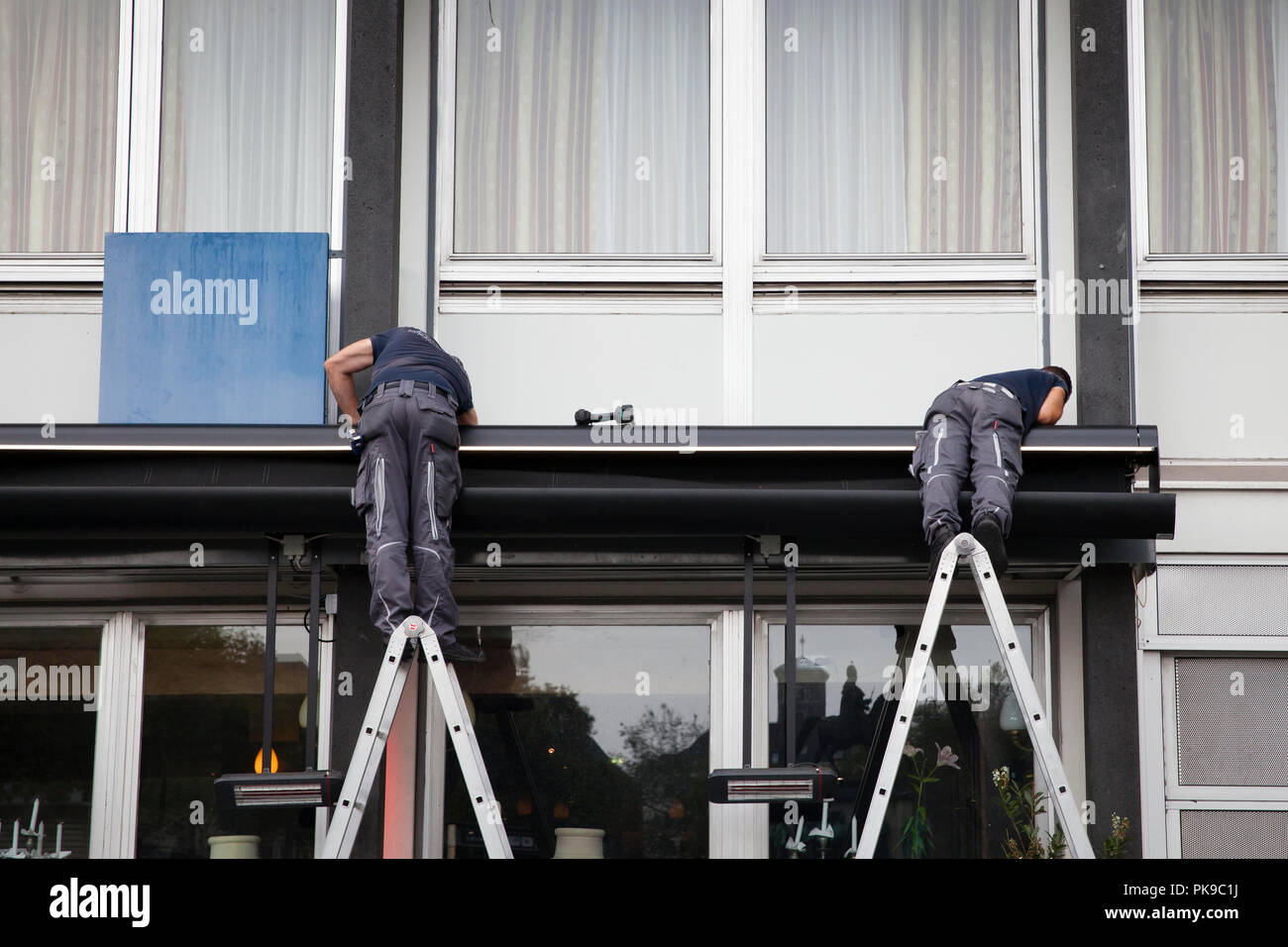 Los trabajadores en las escaleras son el montaje de un toldo en la Heumarket en la parte histórica de la ciudad, Colonia, Alemania. Arbeiter auf Leitern montieren eine Ma Foto de stock