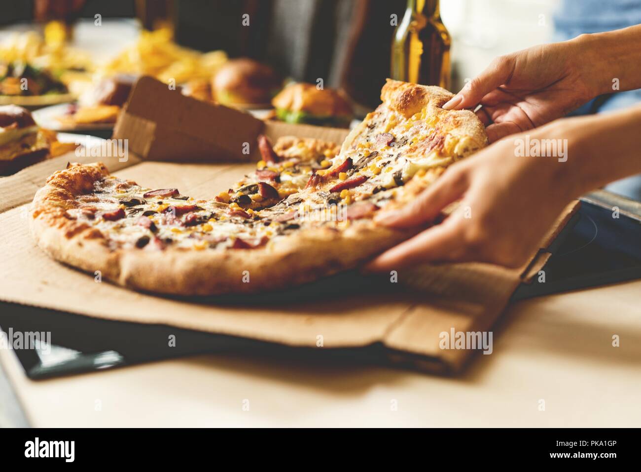 Amigos teniendo cortes de deliciosa pizza de la placa, vista cercana. Foto de stock