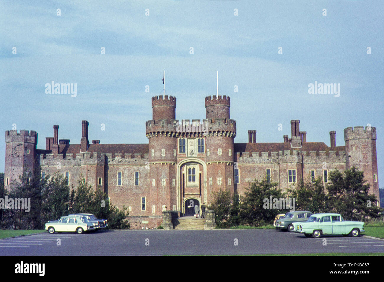 Posiblemente la imagen tomada por un fotógrafo amateur durante un día visitando la casa señorial Castillo de Herstmonceux, Hailsham, East Sussex, durante el período de 1960 hay coches aparcados en el aparcamiento Foto de stock
