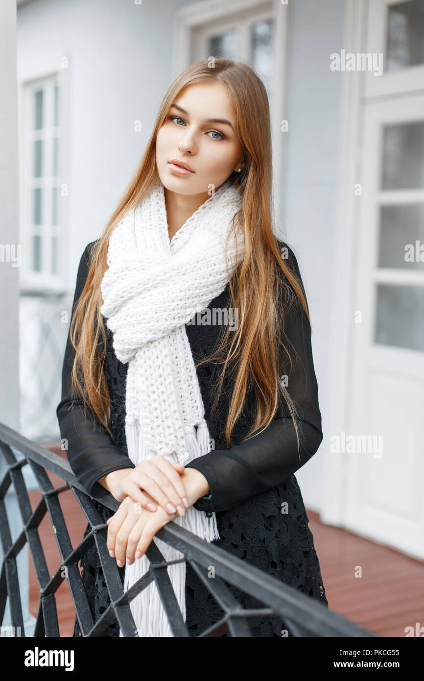 Hermosa chica en una bufanda de punto blanco y negro vestidos de moda de  pie en el porche de la casa Fotografía de stock - Alamy