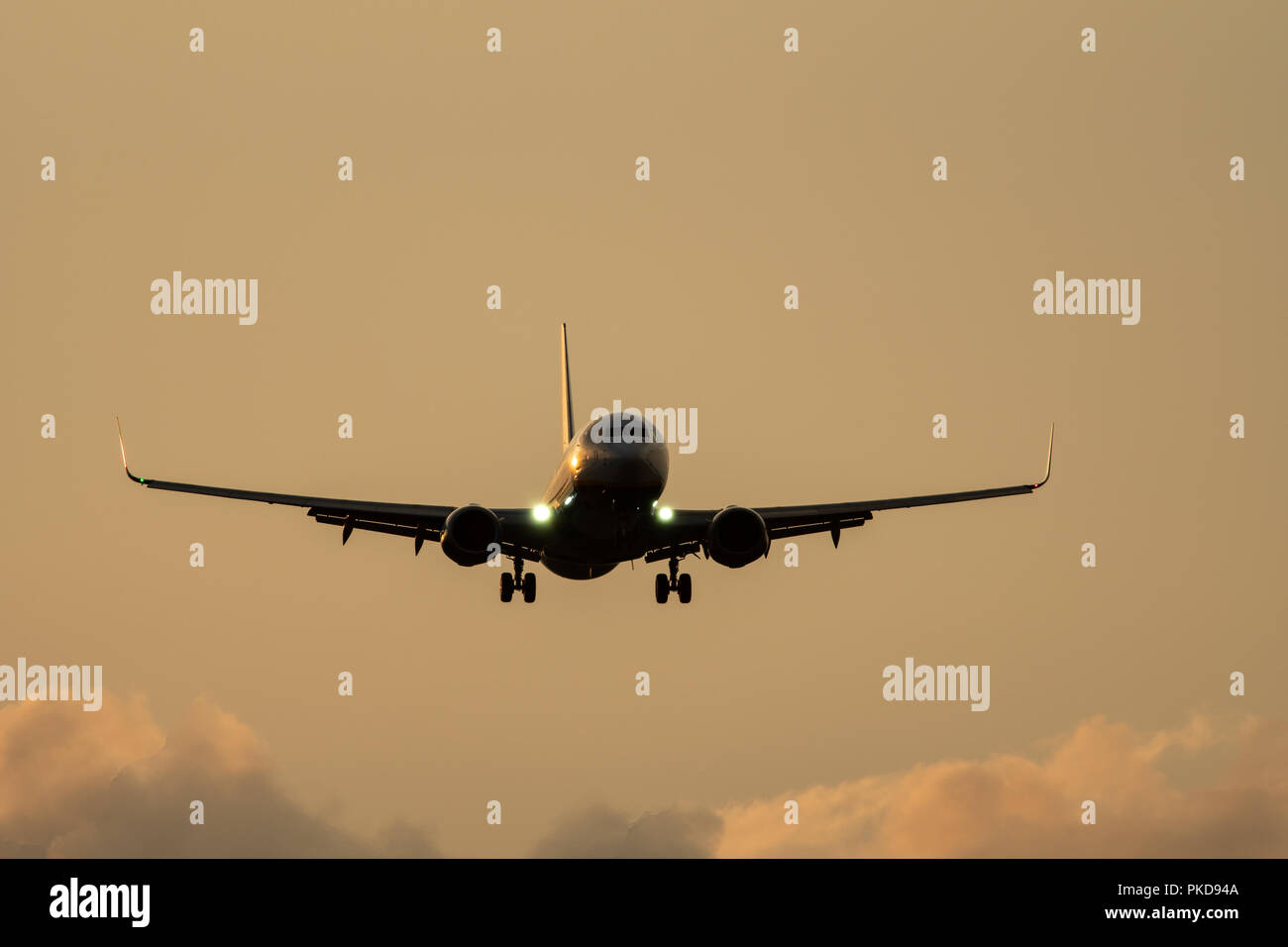 Avión aterrizaba en contra de nubes al atardecer Foto de stock