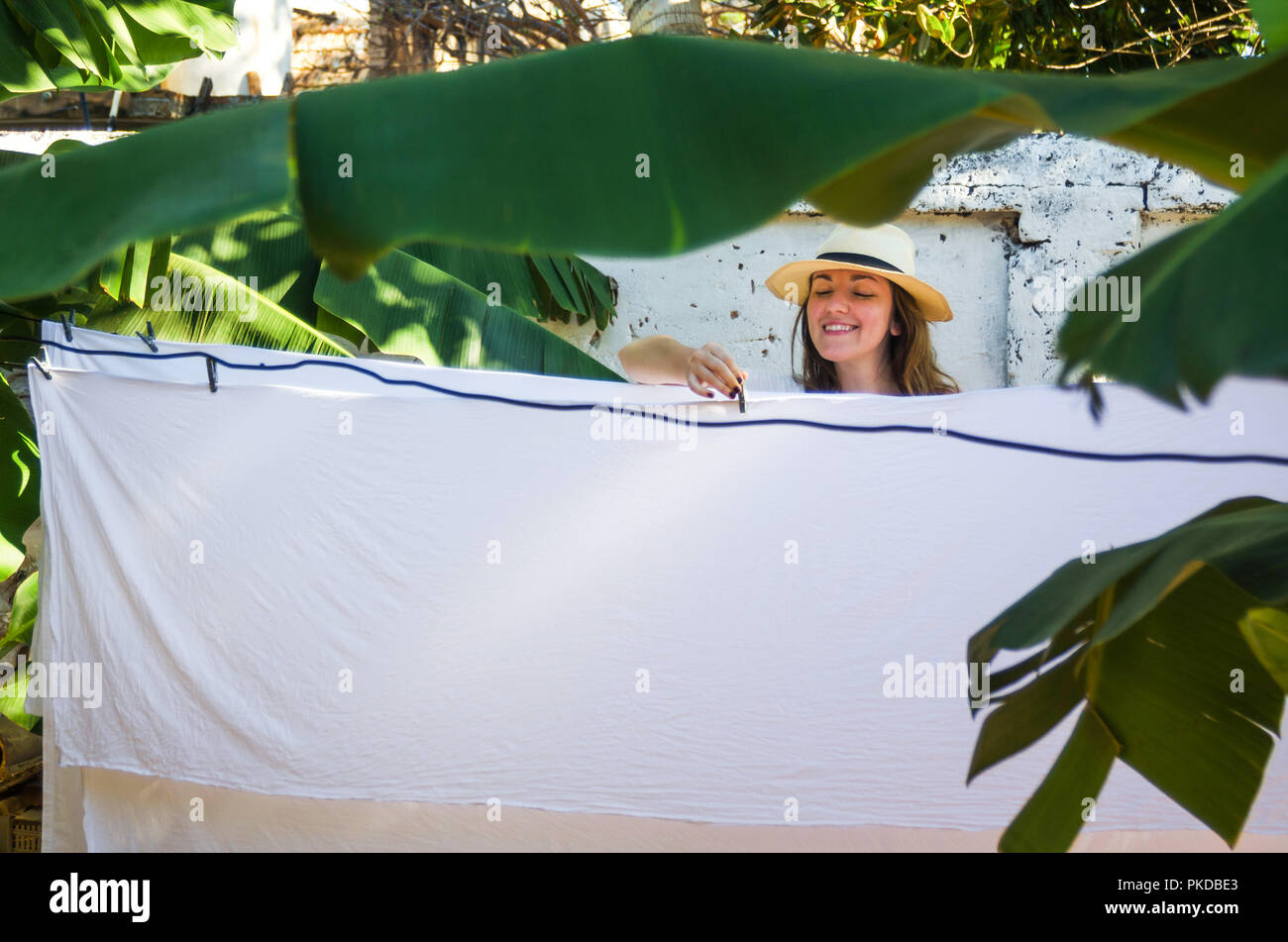 Chica colgando hojas en una línea de ropa exterior Foto de stock