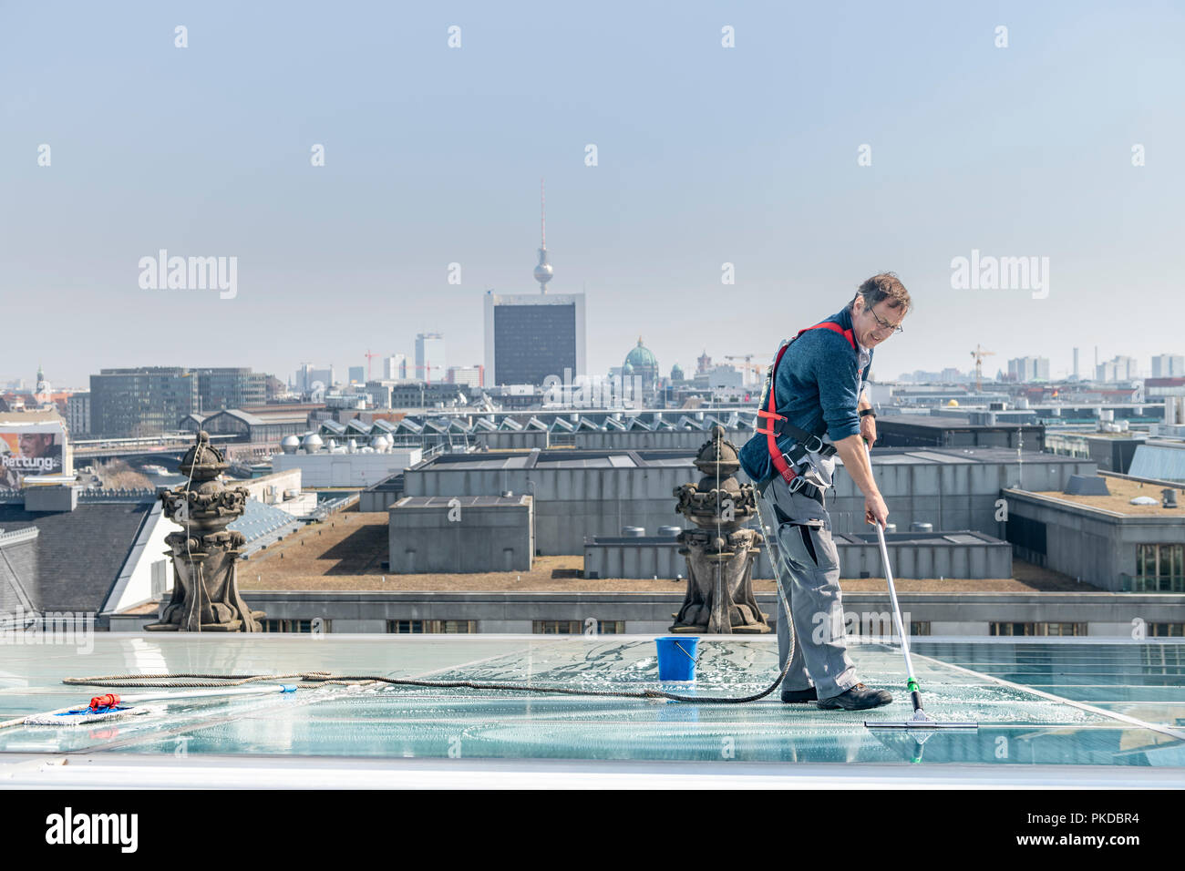 Un hombre limpia las ventanas de techo en la parte superior del edificio del Reichstag en la capital alemana de Berlín. Foto de stock