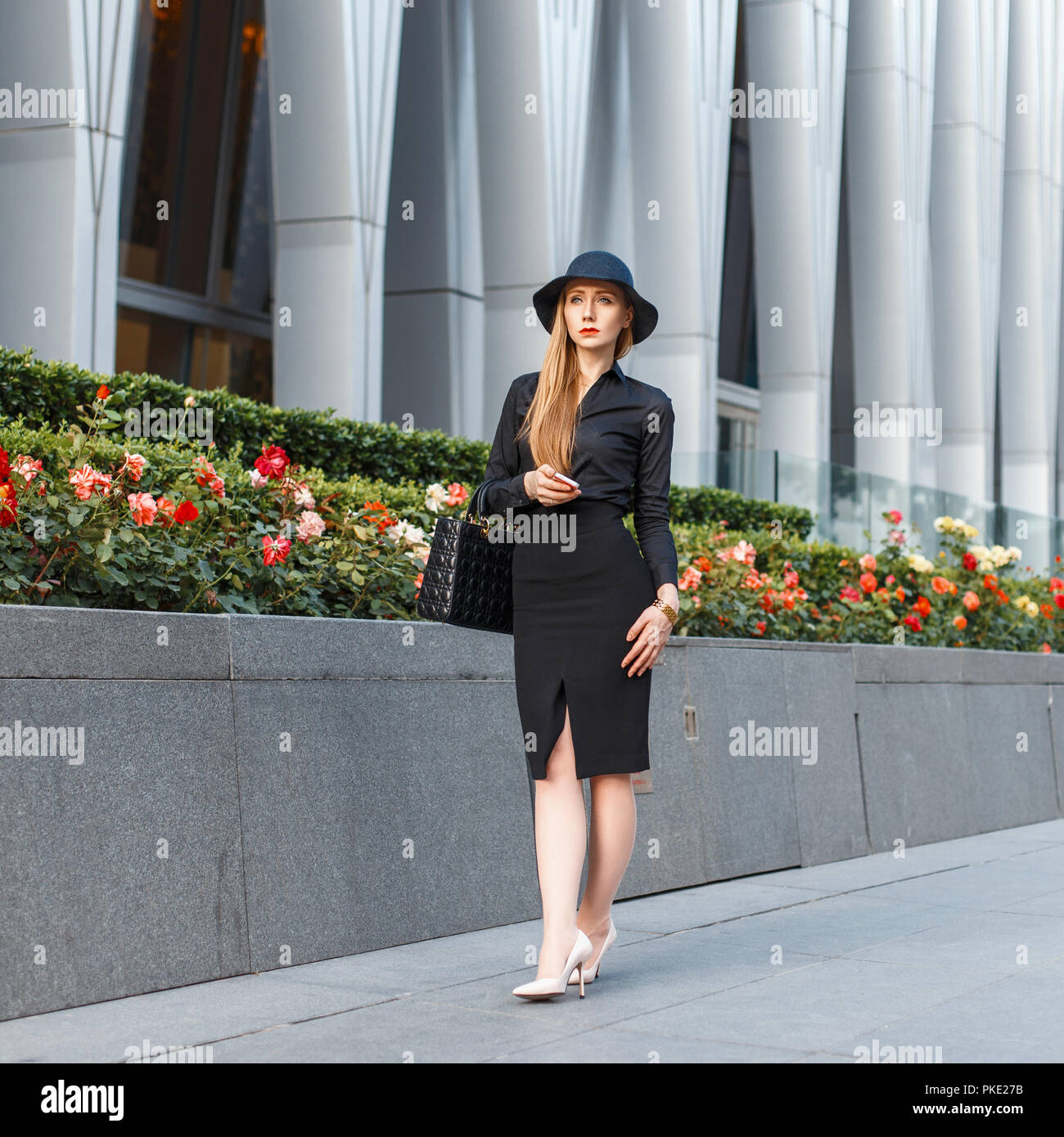 Hermosa mujer elegante en un elegante sombrero en ropa de estilo de  negocios sobre un fondo de un edificio moderno Fotografía de stock - Alamy