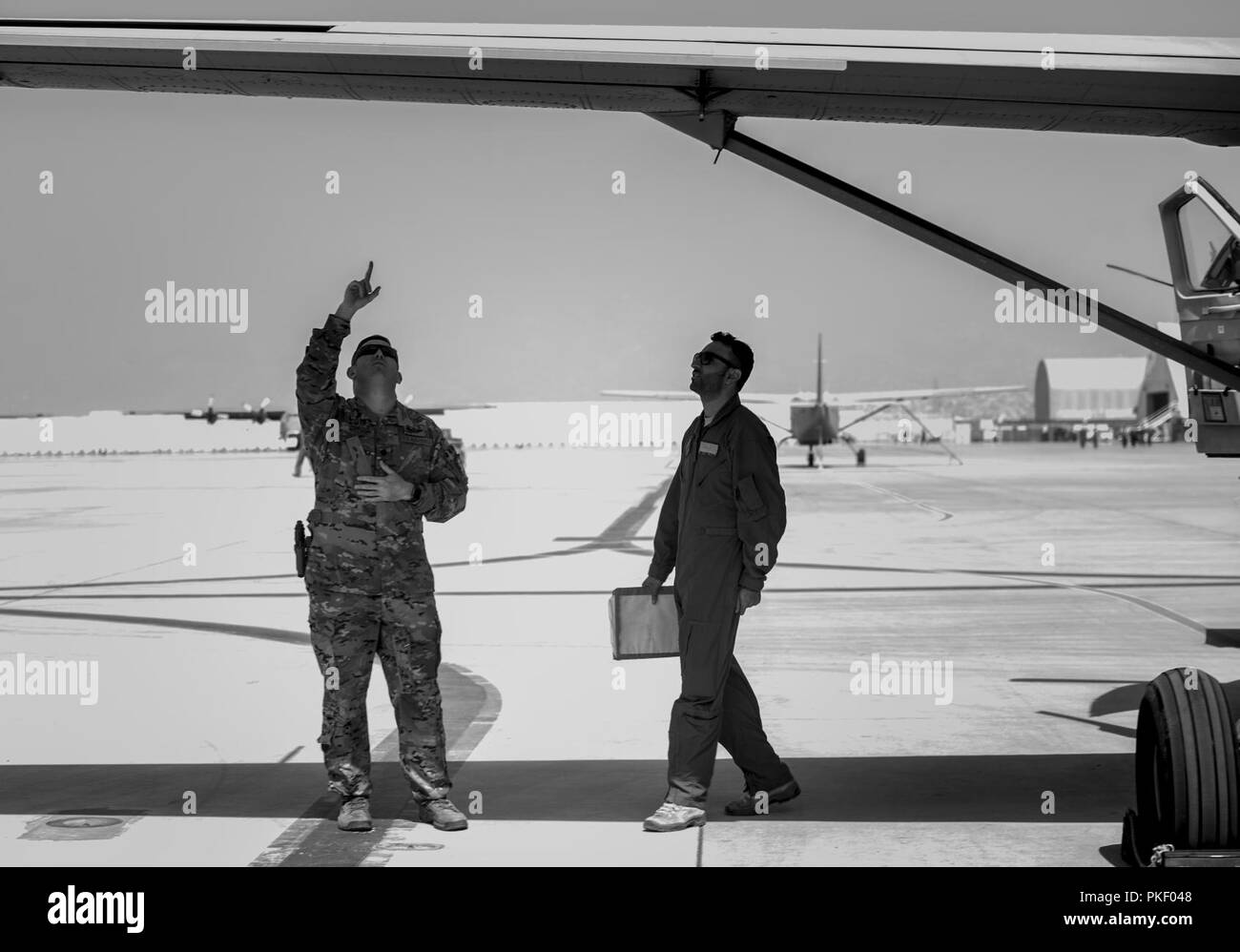 KABUL, Afganistán (25 de julio, 2018) -- un piloto estadounidense (izquierda) asignado a la 438th ala expedicionaria aérea como parte de capacitar, asesorar y ayudar Command-Air (TAAC-aire) y un piloto afgano (derecha) de un Cessna 208B asignada a la 1ª Ala fuerza aérea en Afganistán Hamid Karzai Aeropuerto Internacional (HKIA), Afganistán, inspeccionar las alas del avión antes del despegue el 25 de julio de 2018. La misión de TAAC-Air es capacitar, asesorar y asistir a los socios afganos para desarrollar un profesional, capaz y sostenible de la fuerza aérea afgana. Foto de stock