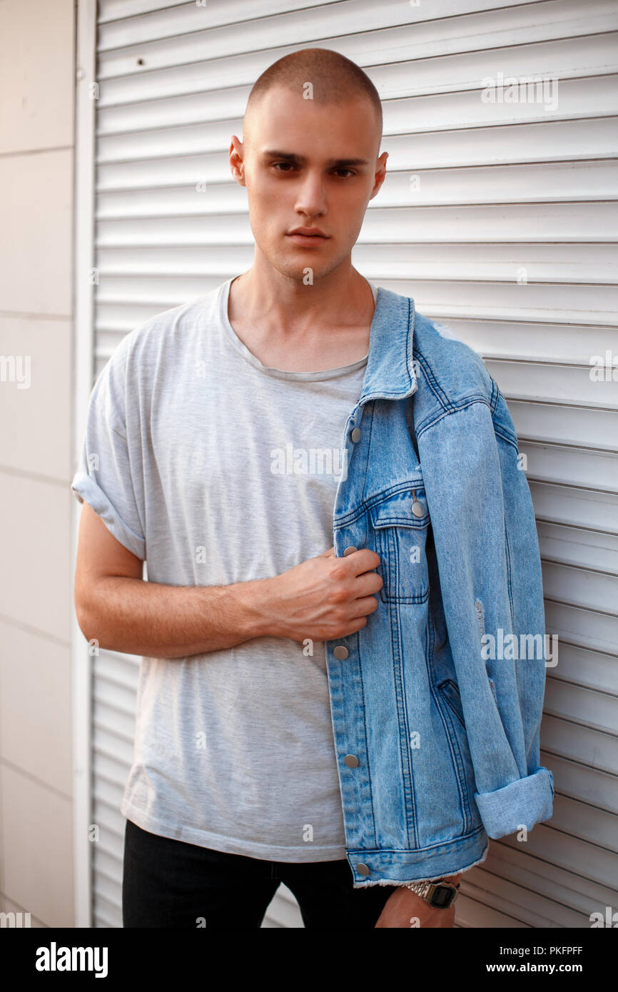 Apuesto joven modelo americano hombre en jeans ropa cerca de pared del bastidor metal blanco Fotografía stock - Alamy