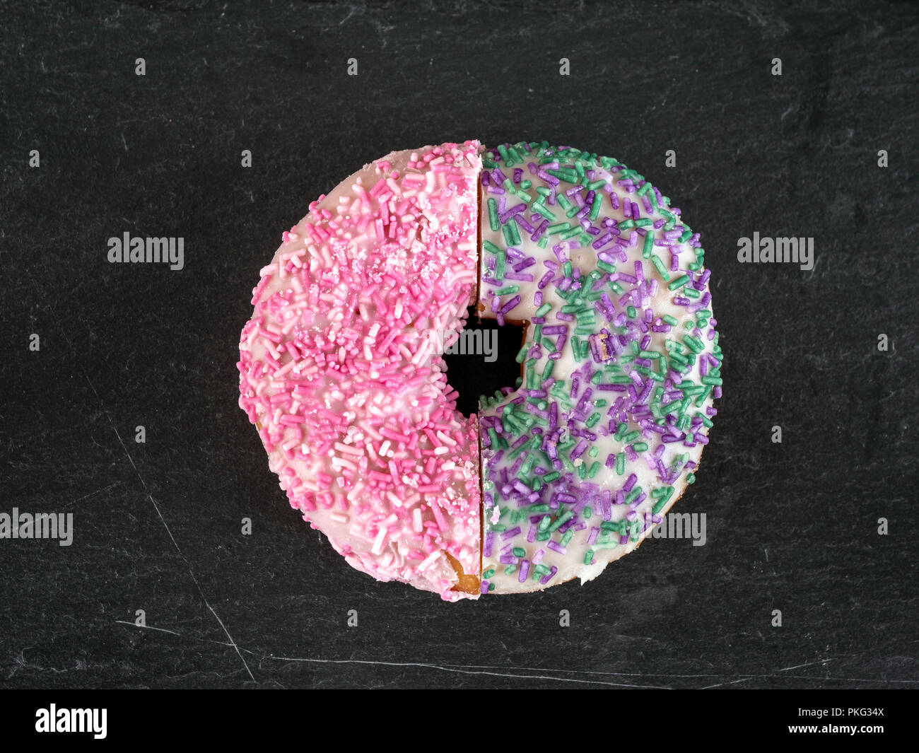 Dos medias donuts cubiertos de hielo y espolvorea juntas para crear un conjunto de anillos Foto de stock