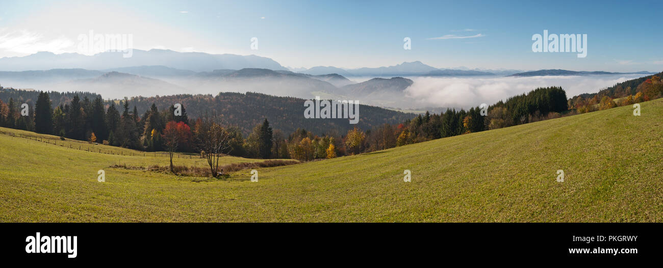 Paisaje otoñal panorama con las montañas nubladas a través del valle cubierto de niebla en el soleado clima en los Alpes austríacos superior. Foto de stock