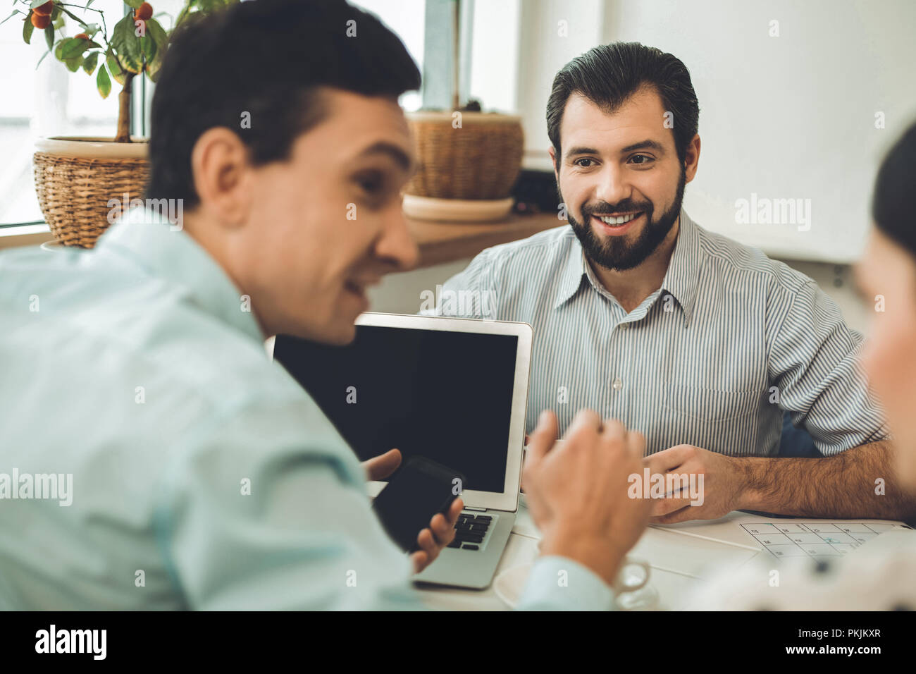 Alegre buen hombre sentado delante del portátil. Foto de stock