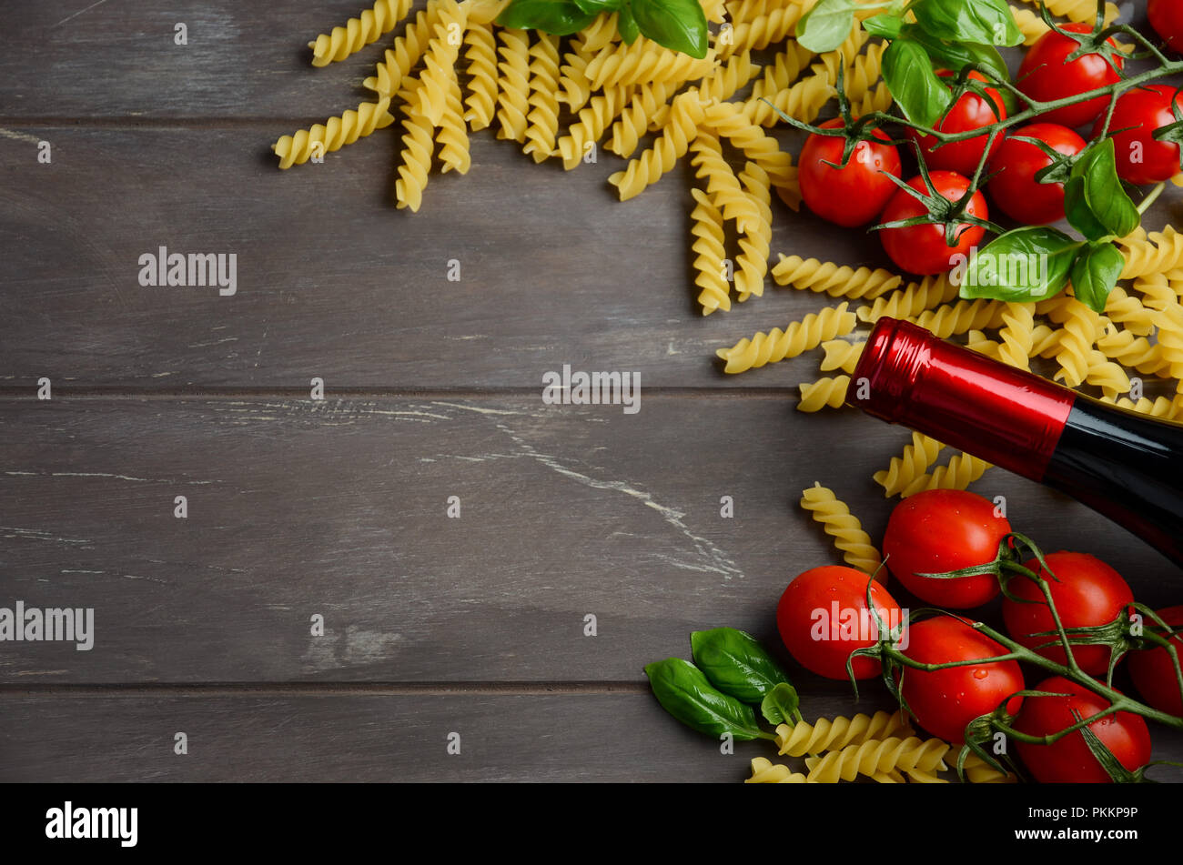 Comida italiana - materias fusilli, tomate, albahaca y vino en la mesa de madera. Foto de stock
