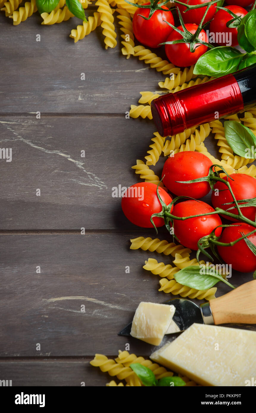 Comida italiana - materias fusilli, tomate, albahaca y vino en la mesa de madera. Foto de stock