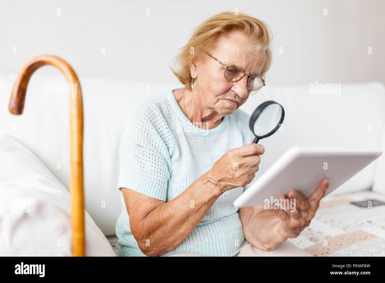 Anciana con gafas y la lupa utilizando una tableta digital moderna  Fotografía de stock - Alamy