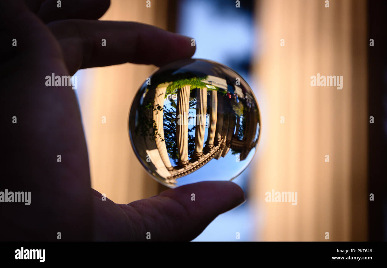 Dedos sosteniendo una esfera de vidrio mostrando los pilares del Palacio de Bellas Artes en San Francisco. Foto de stock