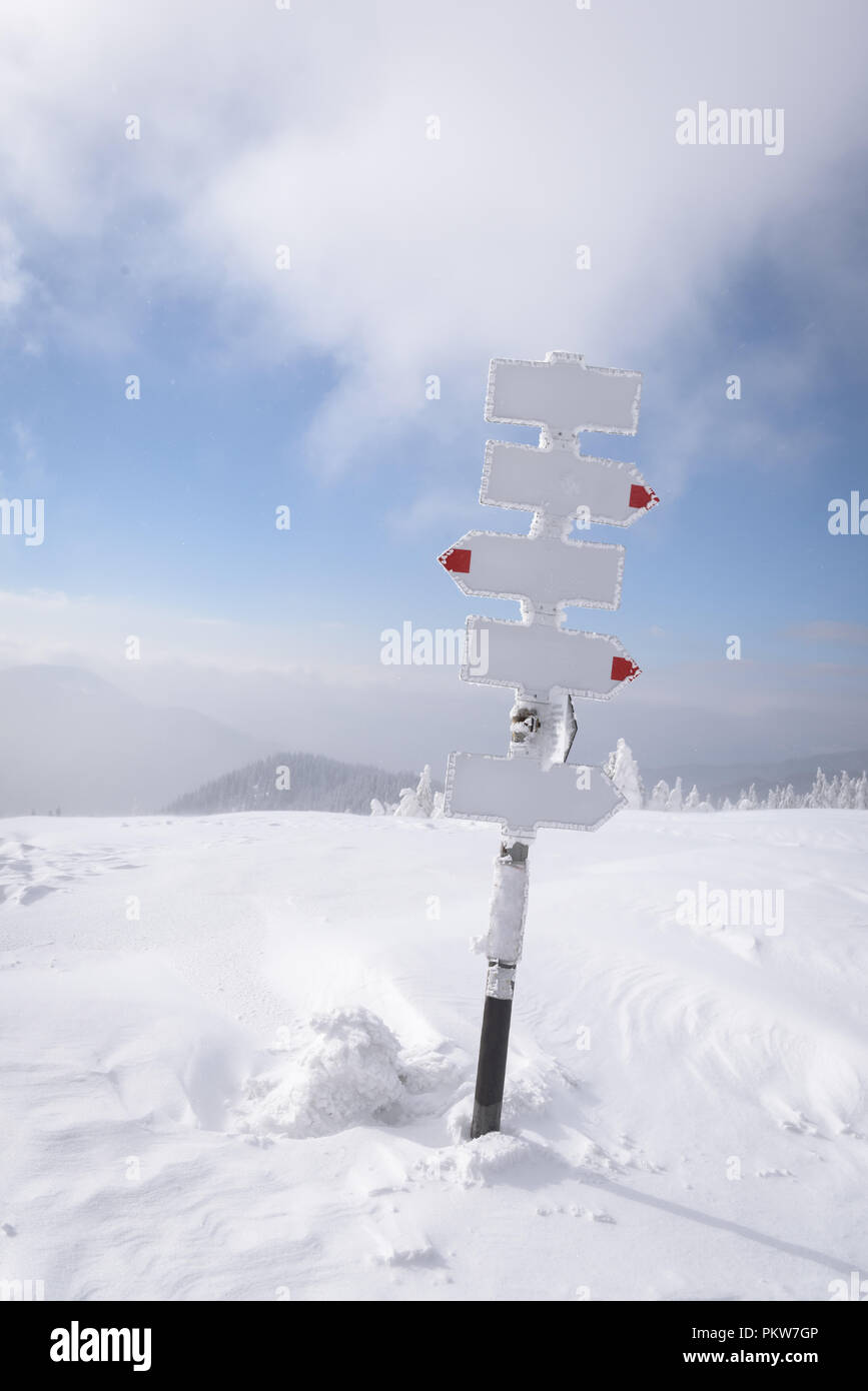 Puntero de metal con flechas en montañas en invierno Foto de stock