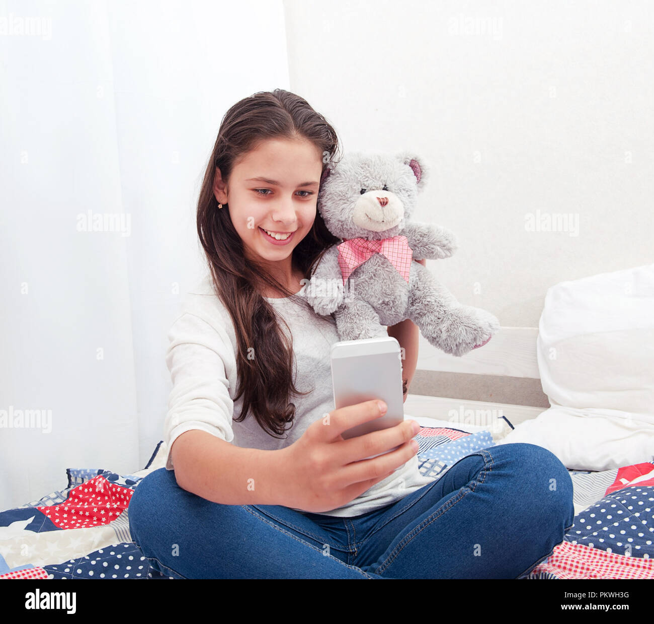 La niña sentada en la cama hace selfie con un oso de peluche Fotografía de  stock - Alamy