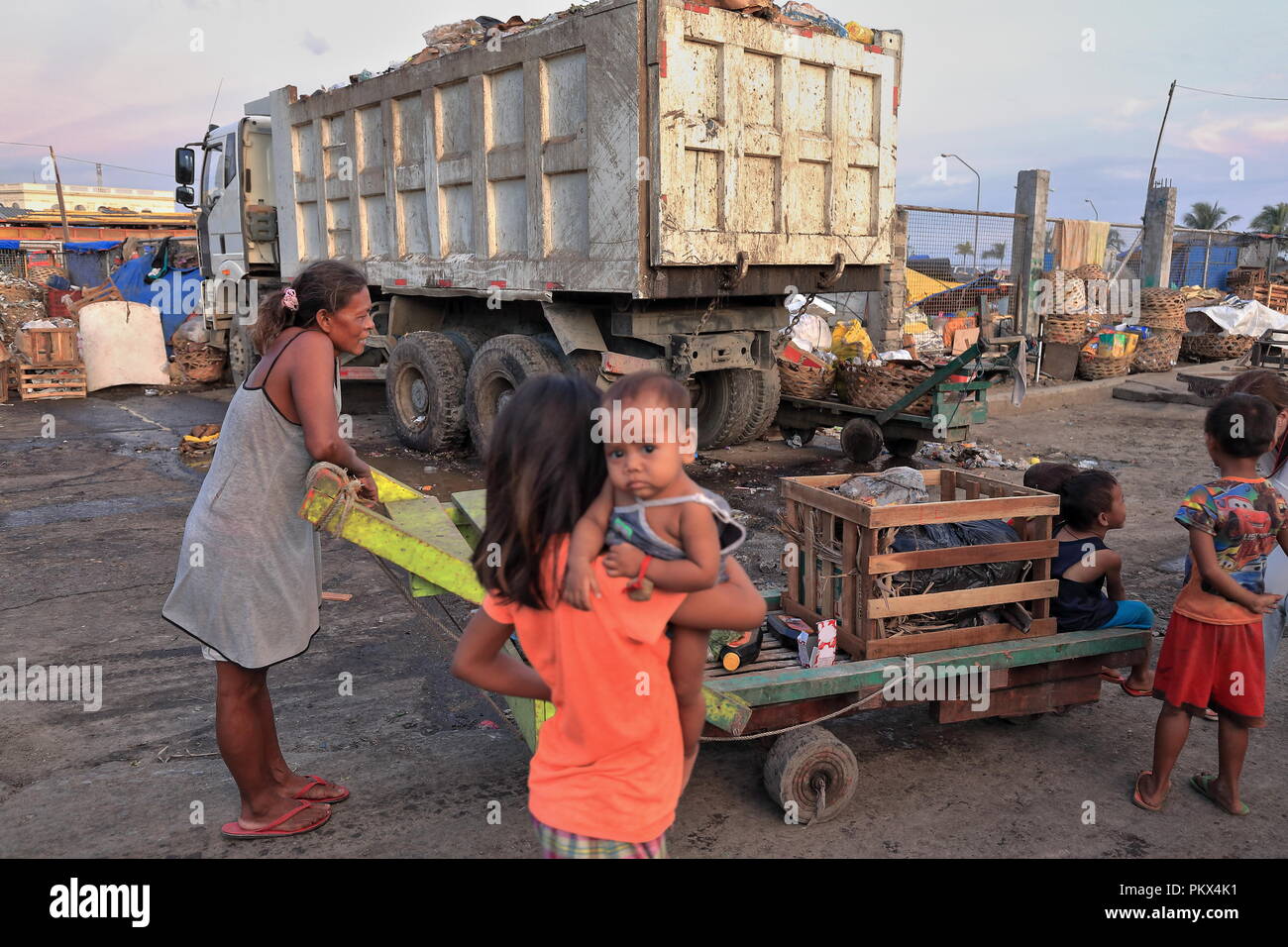 Cebú, Philippines-October 18, 2016: los niños filipinos madre lleva a su casa en una camilla plana a través de los escombros de un día hábil, Mercado de Carbono-lo Foto de stock