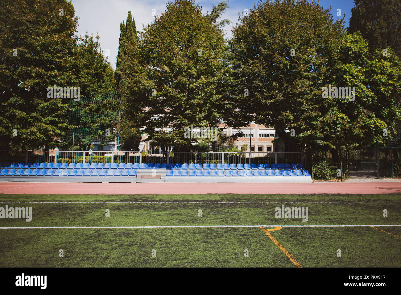 Soporte azul asientos amplia línea de disparo en parque con campo de deportes verde Foto de stock