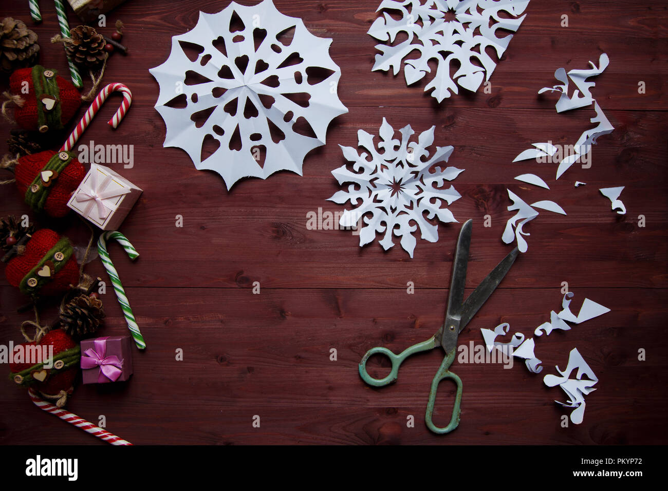 Concepto de Año Nuevo. Los copos de nieve de papel cortado, regalos, tijeras en una mesa de madera espacio de copia Foto de stock