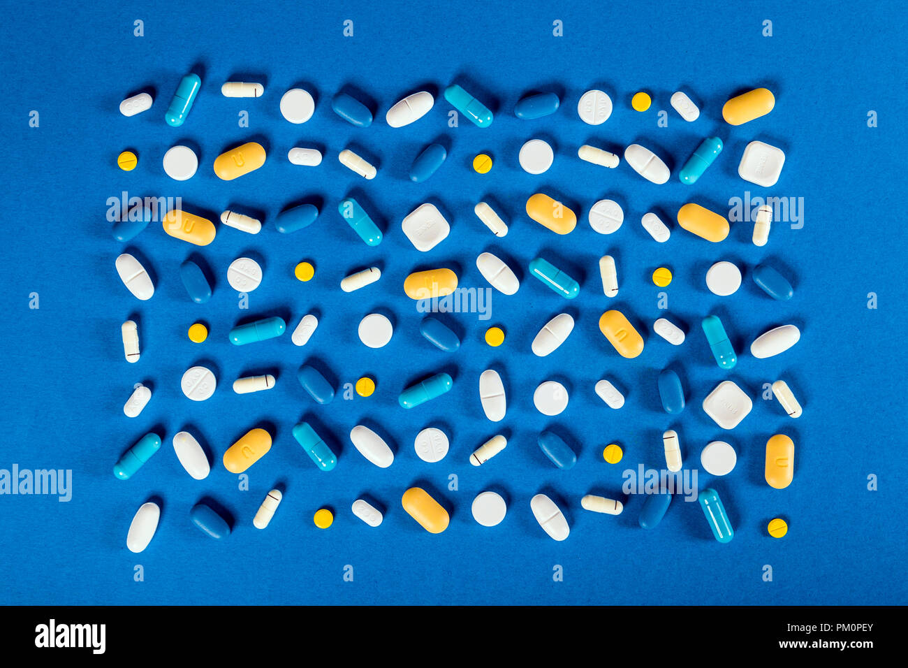 Distribuidos de pastillas, cápsulas y tabletas contra el fondo azul, suplementos, medicamentos, asistencia sanitaria Foto de stock